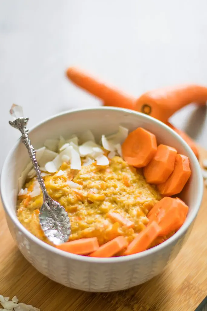 Möhren Porridge in einer Schüssel mit Karotten im Hintergrund