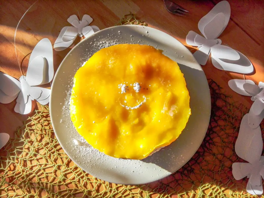 Kokos-Mango-Torte-vegan mit Smiley aus Puderzucker und Schmetterling Deko
