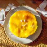 Kokos-Mango-Torte-vegan-mit-Gesicht Kokos-Mango-Torte-vegan mit Smiley aus Puderzucker und Schmetterling Deko