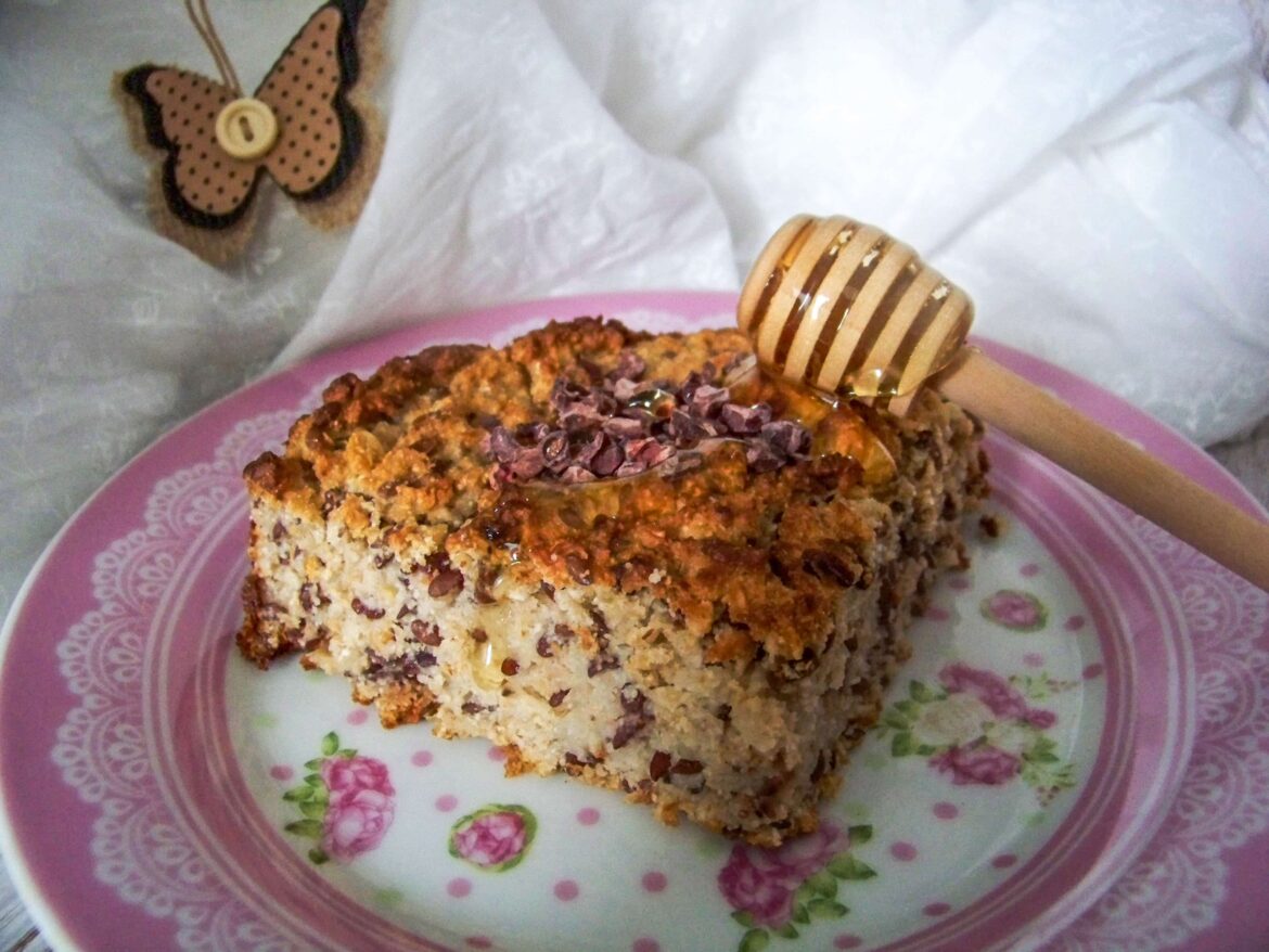 Frühstückskuchen-mit-Haferflocken-und-Leinsamen -Kuchenstück auf Teller mit Honiglöffel