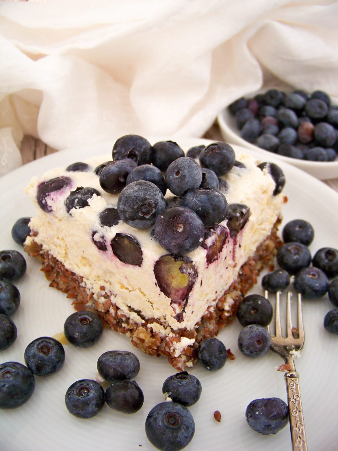Veganer Cashew-Käsekuchen Stück auf einem Teller mit Blaubeeren