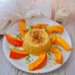 Ofenkürbis-mit-Sesampolenta Ofenkürbis mit Sesampolenta- Kürbisspalten auf einem Teller mit Polentaturm