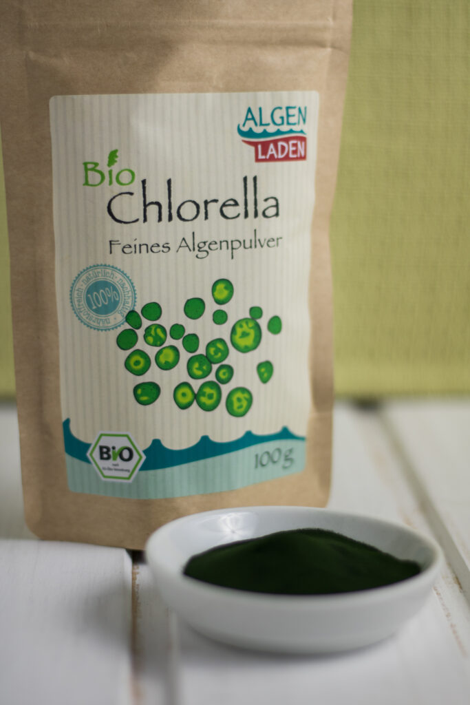 Bio Chlorella Pulver aus dem Algenladen in der Verpackung und auf einem Teller