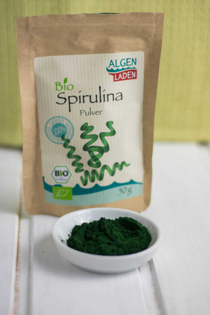 Bio Spirulina Pulver in der Verpackung und auf einem Teller