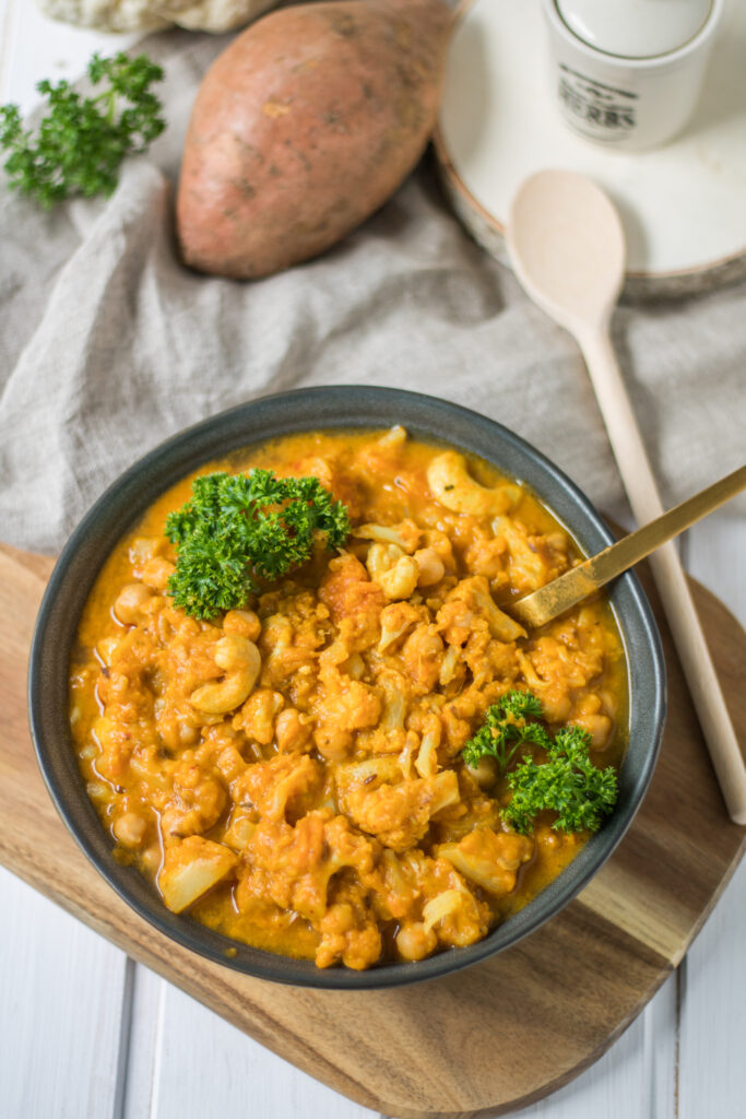 veganes Blumenkohl-Kichererbsen-Curry mit Süßkartoffel von oben mit Kochlöffel