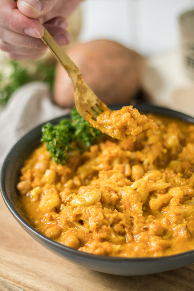 veganes Blumenkohl-Kichererbsen-Curry mit Süßkartoffel Nahaufnahme mit Gabel