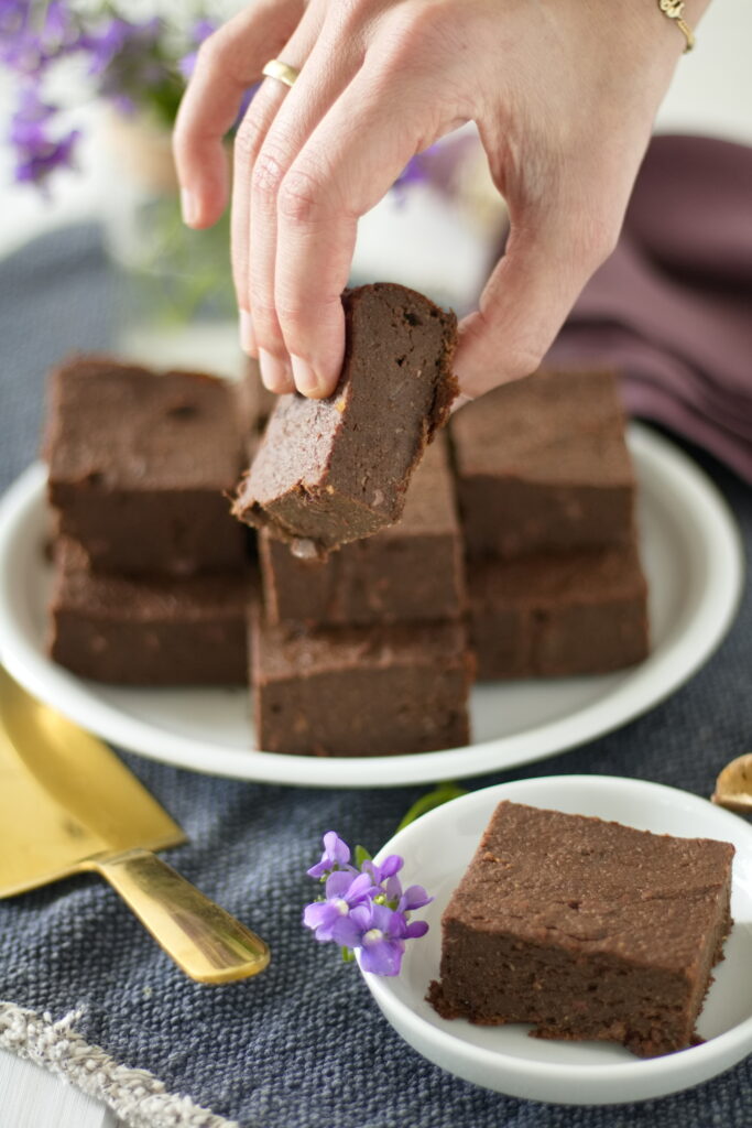 Hand nimmt sich Stück Vegane und glutenfreie Süßkartoffel Brownies mit Datteln