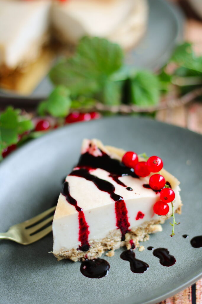 Veganer Käsekuchen ohne Soja - Kuchenstück mit Beerensoße